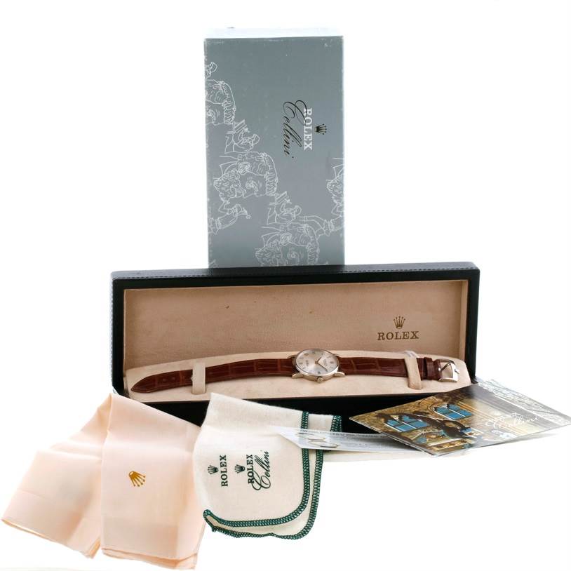 The Rolex Cellini 5115 Men's White Gold Silver Dial 5115 Men's White Gold Silver Dial watch is displayed in its box with accompanying accessories, including cloths, manuals, and original packaging.
