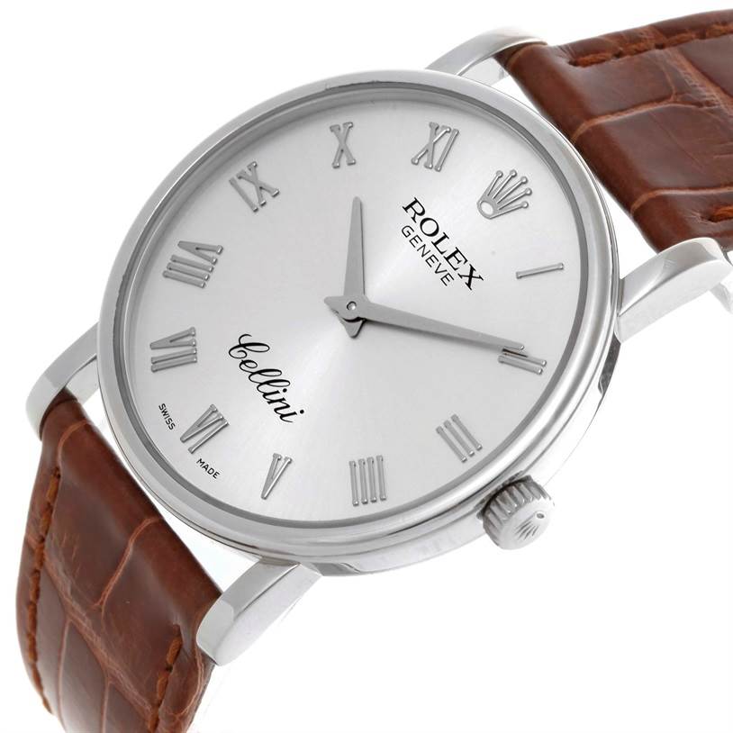 The Rolex Cellini 5115 Men's White Gold Silver Dial 5115 Men's White Gold Silver Dial watch is shown at an angled view, highlighting its silver dial, Roman numerals, and brown leather strap.