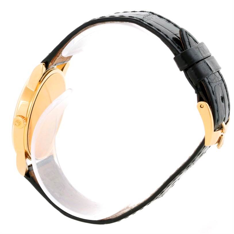 This image shows a side view of the Rolex Cellini 5116 Men's Yellow Gold Beige Dial 5116 Men's Yellow Gold Beige Dial watch, highlighting the bezel, crown, and black leather strap.