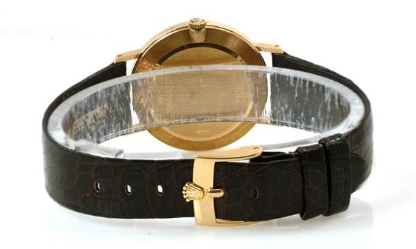 The image shows the back view of a Cellini model by Rolex, featuring the watch case and leather strap with a gold clasp.