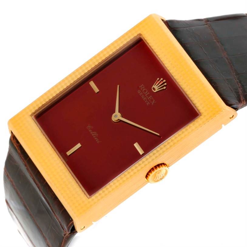 The image shows a close-up, angled shot of the Rolex Cellini 4127 Men
s Yellow Gold Champagne Dial 4127 Men
s Yellow Gold Champagne Dial watch, highlighting its rectangular dial, gold casing, and brown strap.