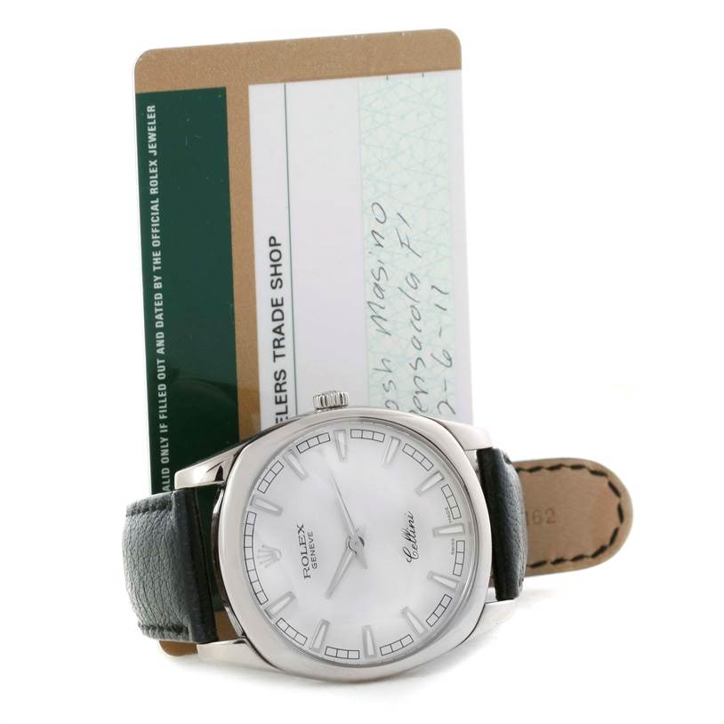 The Rolex Cellini 4243 Men's White Gold Silver Dial 4243 Men's White Gold Silver Dial watch is shown from the front, displaying its dial, case, and part of its leather strap, alongside a warranty card.