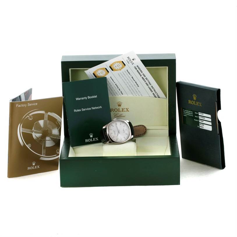 The image shows a Rolex Cellini 4243 Men's White Gold Silver Dial 4243 Men's White Gold Silver Dial watch inside its open box, along with warranty booklets and service manuals displayed around it.