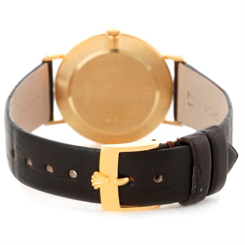 The image shows the back of a Rolex Cellini 4112 Men
s Yellow Gold Grey Dial 4112 Men
s Yellow Gold Grey Dial watch, highlighting its gold case and leather strap with a buckle.