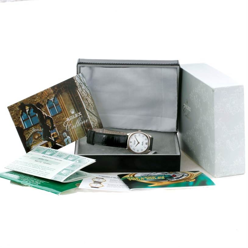 The image shows a Rolex Cellini 4233 Men
s White Gold White Dial 4233 Men
s White Gold White Dial watch displayed in its box, accompanied by booklets and documents.