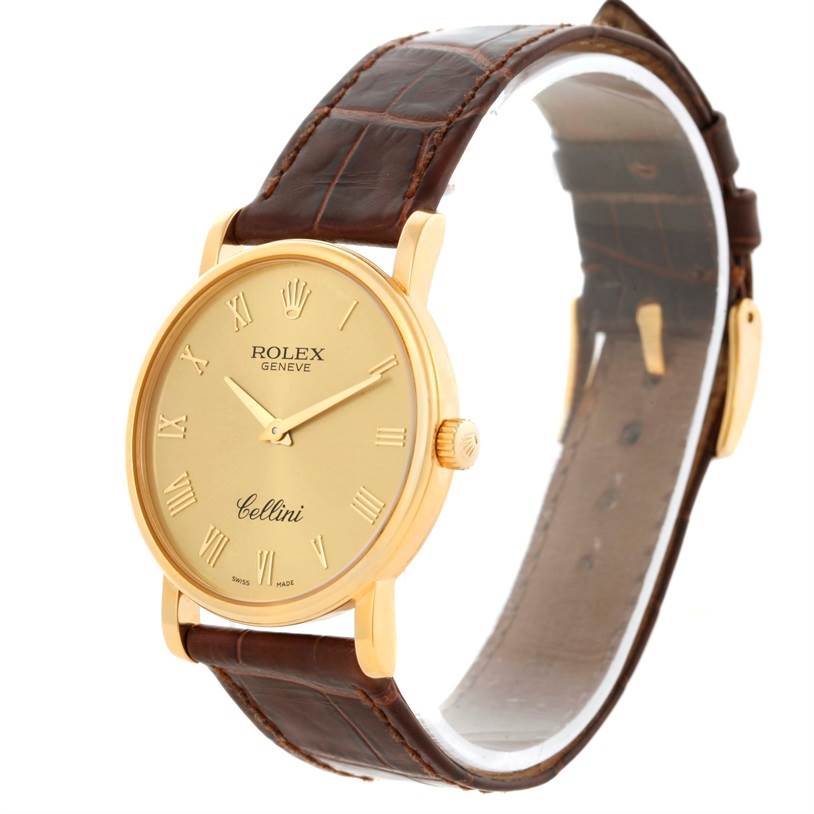 The image shows a angled top-left view of a Rolex Cellini 5115 Men
s Yellow Gold Champagne Dial 5115 Men
s Yellow Gold Champagne Dial watch showcasing its gold dial, Roman numerals, and brown leather strap.