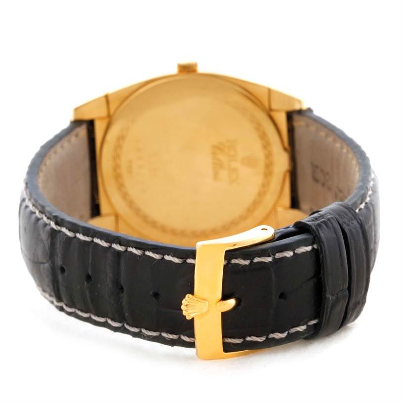 The image shows the back view of a Rolex Cellini 5330 Men's Yellow Gold White Dial 5330 Men's Yellow Gold White Dial watch with a gold case and a black leather strap featuring a gold buckle.