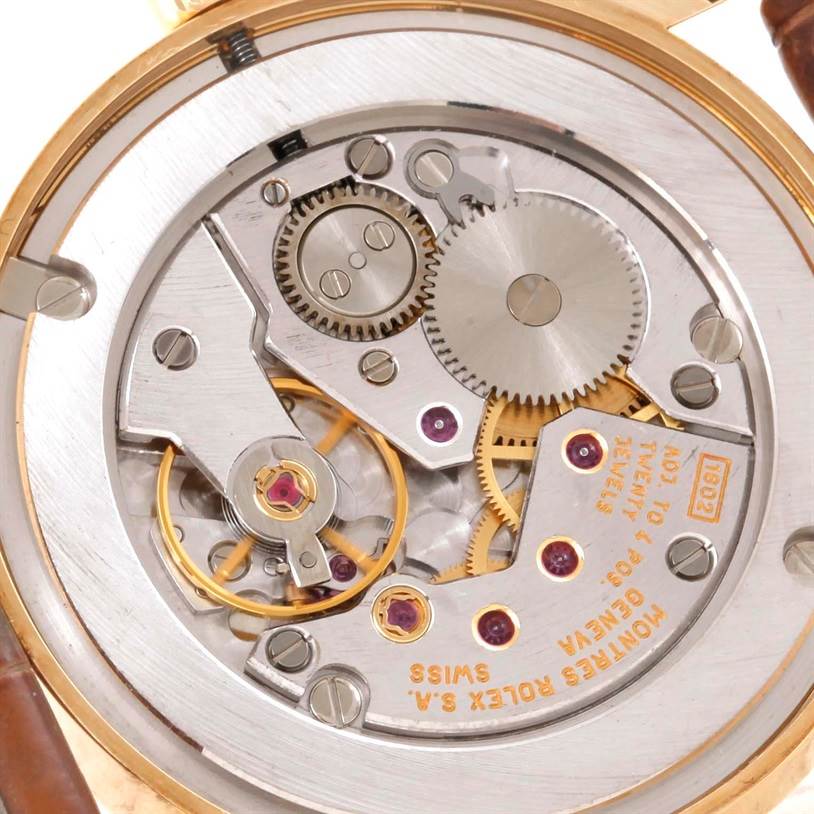 The image shows the inner mechanism of a Rolex Cellini 5115 Men
s Yellow Gold Beige Dial 5115 Men
s Yellow Gold Beige Dial watch, featuring gears, jewels, and the movement components.