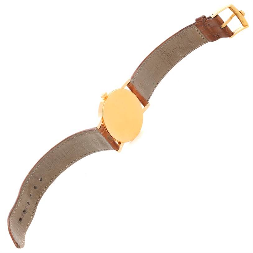 The image shows the back of a Rolex Cellini 5115 Men
s Yellow Gold Beige Dial 5115 Men
s Yellow Gold Beige Dial watch with its leather strap and gold case.