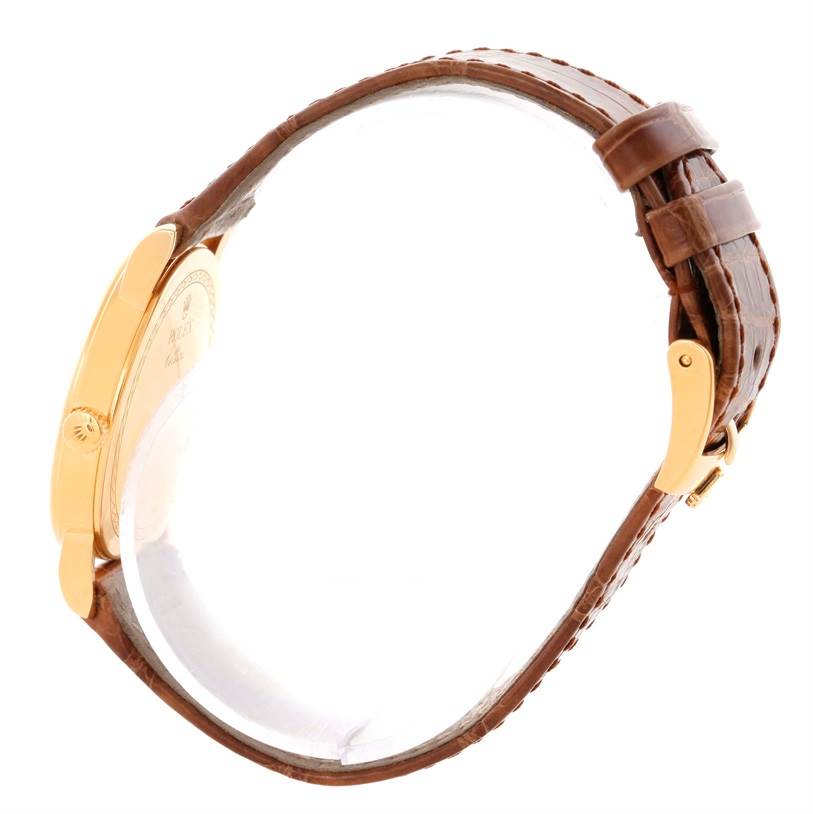 The image shows a side view of a Rolex Cellini 5115 Men
s Yellow Gold Champagne Dial 5115 Men
s Yellow Gold Champagne Dial watch, highlighting its gold case and brown leather strap with a buckle.