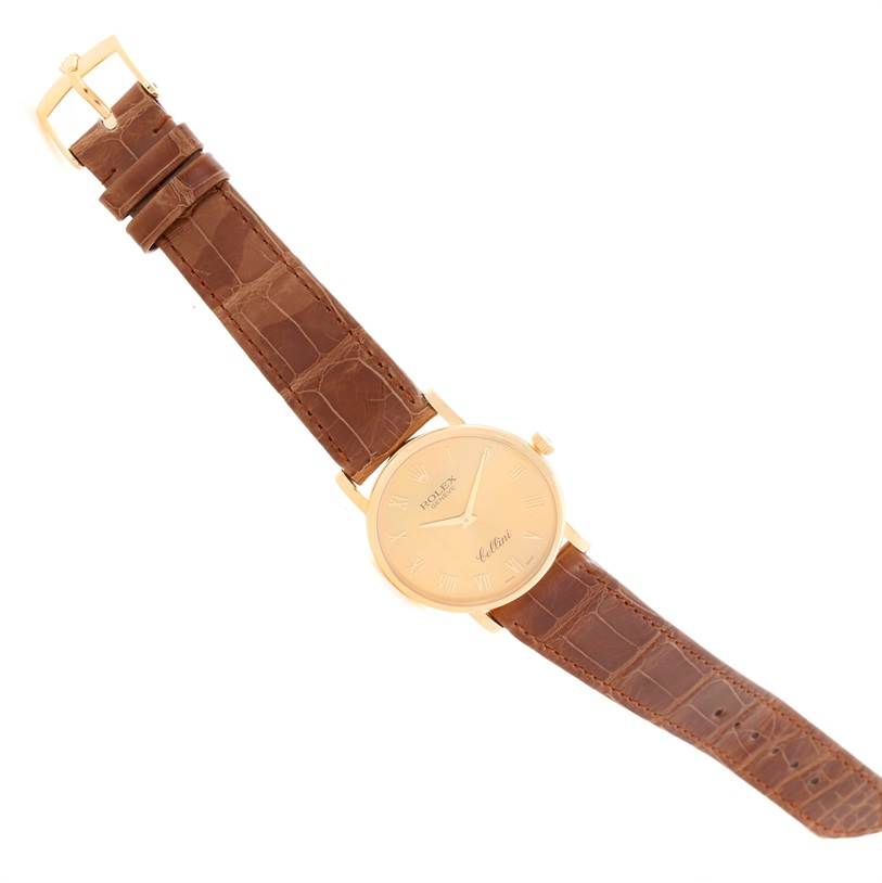 The image shows a top-down view of a Rolex Cellini 5115 Men
s Yellow Gold Champagne Dial 5115 Men
s Yellow Gold Champagne Dial watch with a brown leather strap and gold case, buckle, and dial.