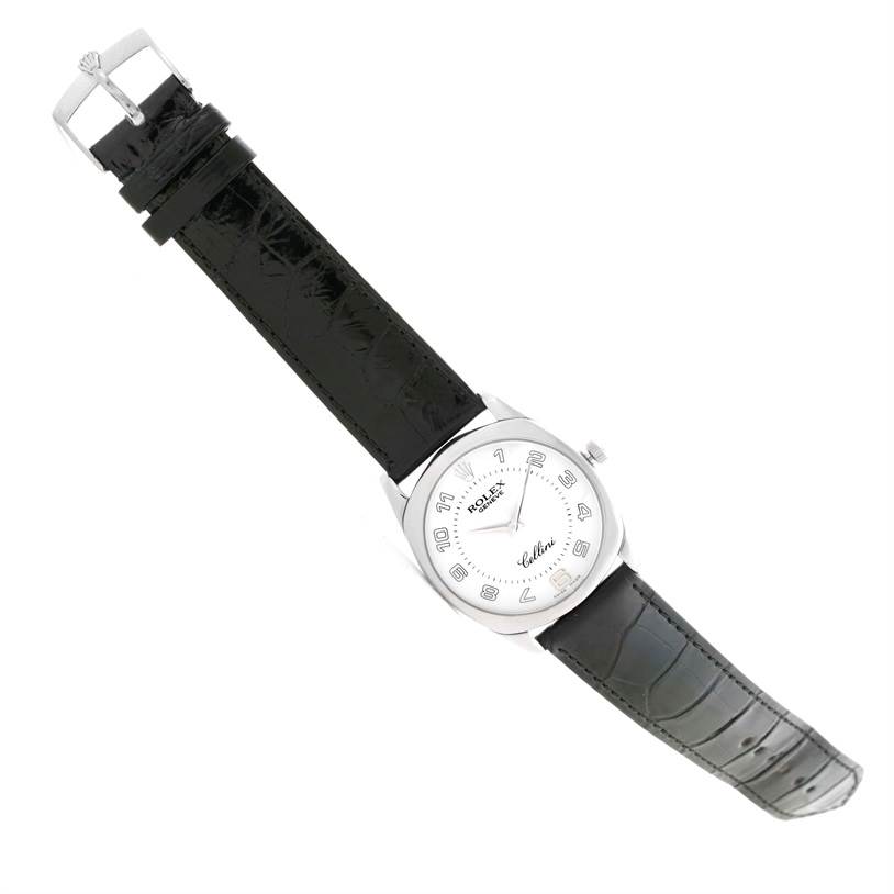 The image shows a Rolex Cellini 4233 Men
s White Gold White Dial 4233 Men
s White Gold White Dial watch from a top-down angle, displaying its dial, case, and black leather strap.
