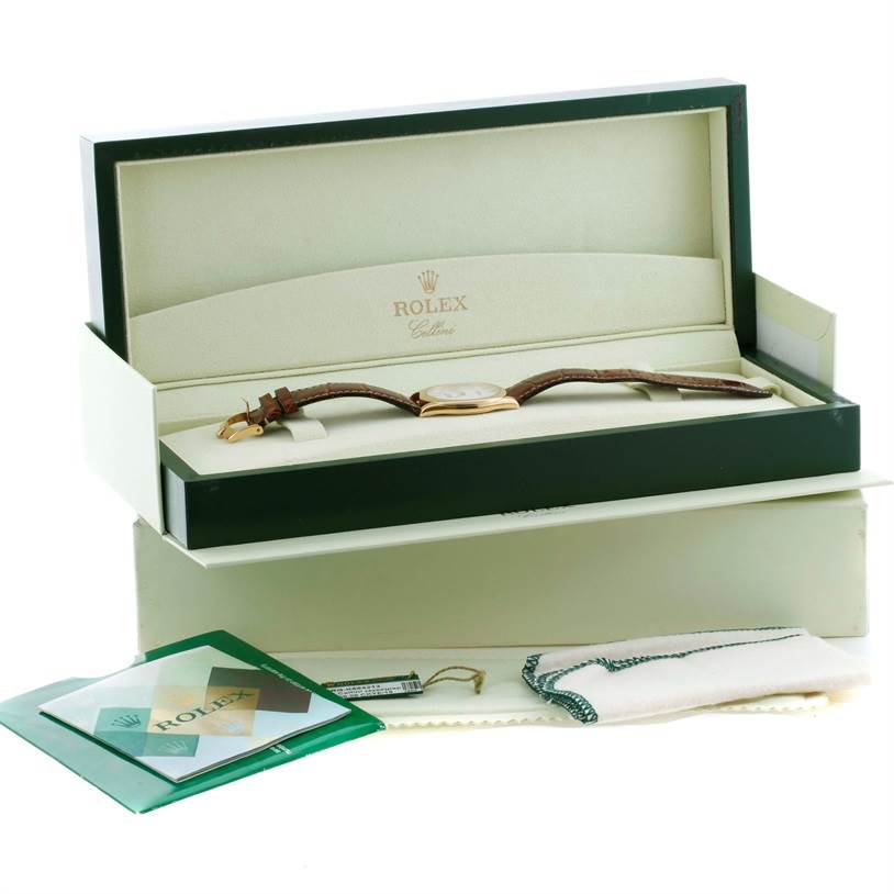 The image shows a Rolex Cellini 4233 Men's Yellow Gold White Dial 4233 Men's Yellow Gold White Dial watch in its open box with additional accessories like a booklet, tag, and cloth.