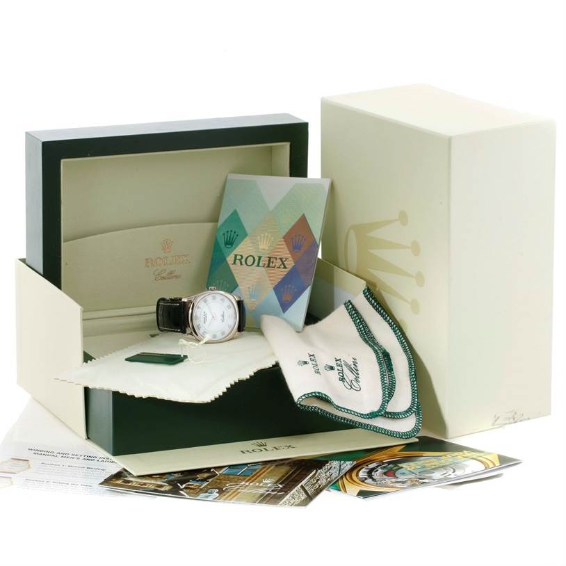 This image shows the Rolex Cellini 4233 Men
s White Gold White Dial 4233 Men
s White Gold White Dial watch from a front angle, with its box, cleaning cloth, manual, and additional accessories.