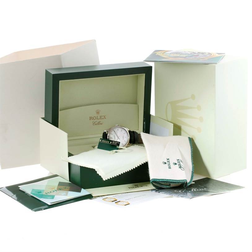 The image shows a Rolex Cellini 4243 Men
s White Gold Silver Dial 4243 Men
s White Gold Silver Dial watch in its box, accompanied by a cleaning cloth, manuals, and packaging material.