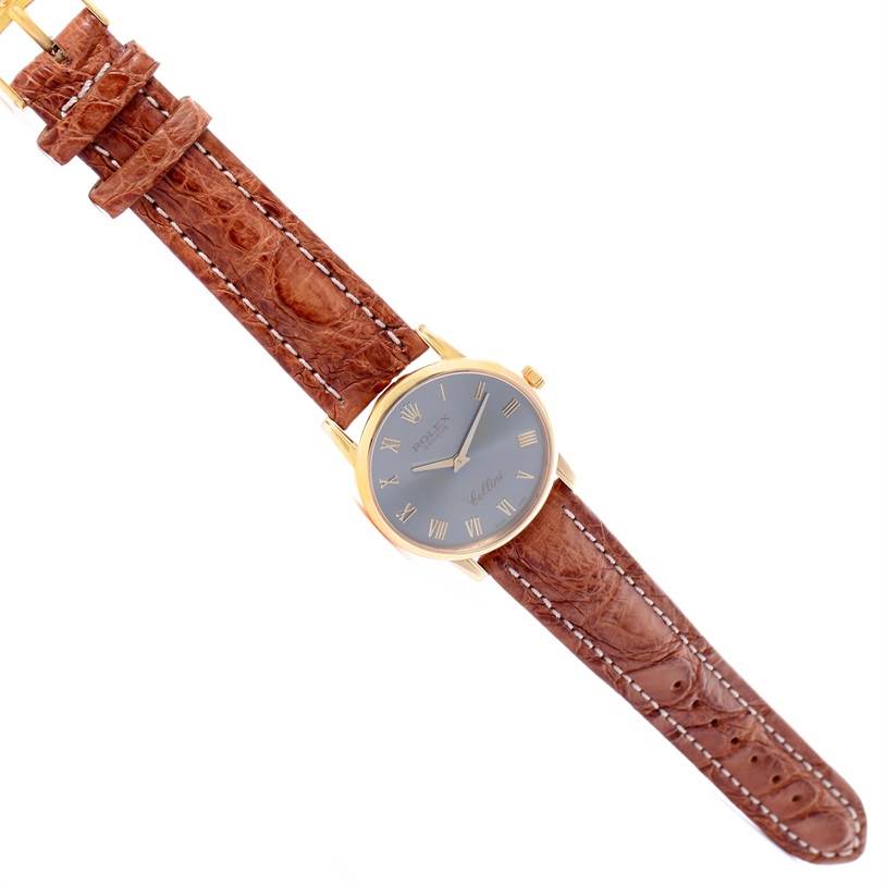 This image shows a top-down view of a Rolex Cellini 5116 Yellow Gold Grey Dial 5116 Yellow Gold Grey Dial watch, featuring its brown leather strap and gold case with a grey dial.