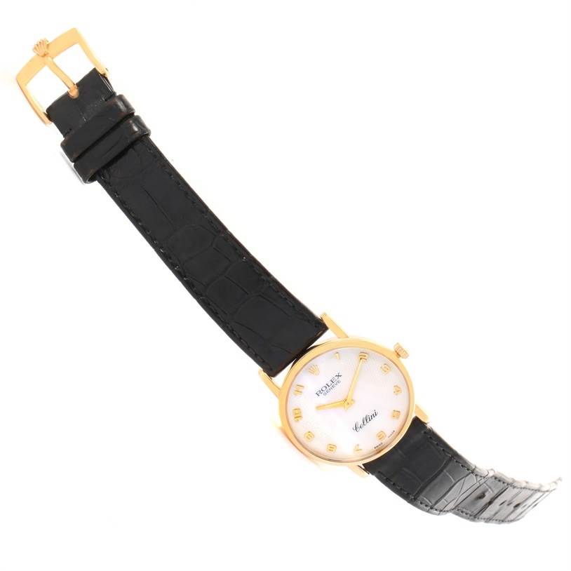 The image shows a Rolex Cellini 5115 Yellow Gold Mother of Pearl Dial 5115 Yellow Gold Mother of Pearl Dial watch at an angle, displaying its black leather strap, gold case, and white dial with Roman numerals.