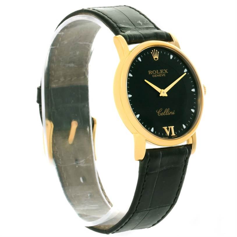 The Rolex Cellini 5115 Yellow Gold Black Dial 5115 Yellow Gold Black Dial watch is shown from a slight side angle, highlighting its black face, gold case, and black leather strap.