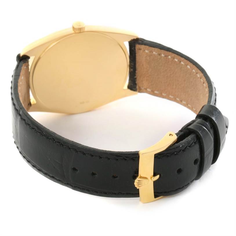 The image shows the back of a Rolex Cellini 4233 Yellow Gold White Dial 4233 Yellow Gold White Dial watch, featuring a black leather strap and a gold clasp.