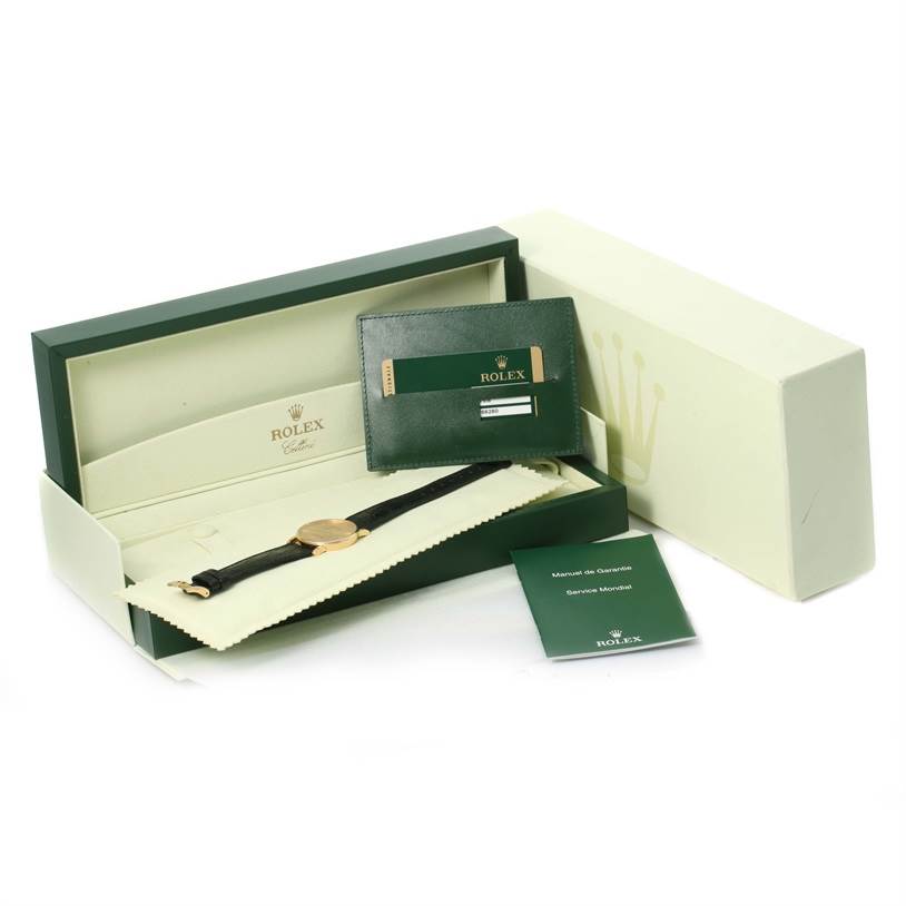 The image shows a Rolex Cellini 5115 Men's Yellow Gold Champagne Dial 5115 Men's Yellow Gold Champagne Dial watch with its packaging, including a green box, warranty card, and a manual.