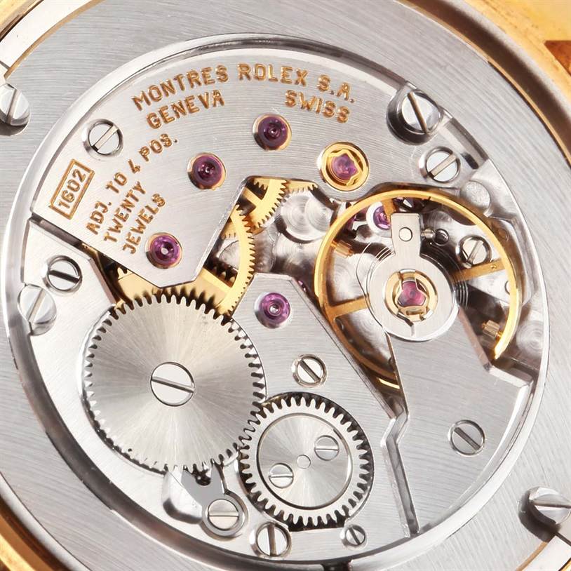 This image shows the intricate movement mechanism of a Rolex Cellini 5116 Men's Yellow Gold Beige Dial 5116 Men's Yellow Gold Beige Dial watch, featuring gears, jewels, and engravings. 