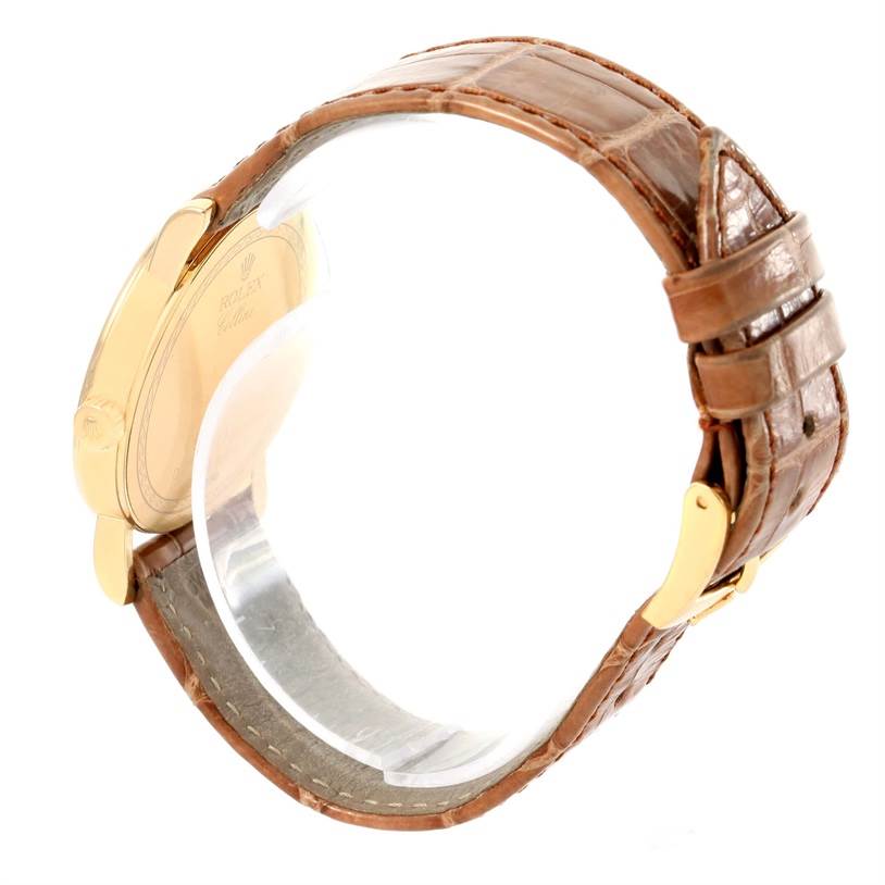 The image shows the Rolex Cellini 5115 Men
s Yellow Gold Champagne Dial 5115 Men
s Yellow Gold Champagne Dial watch from a side angle, highlighting its brown leather strap and gold case back.