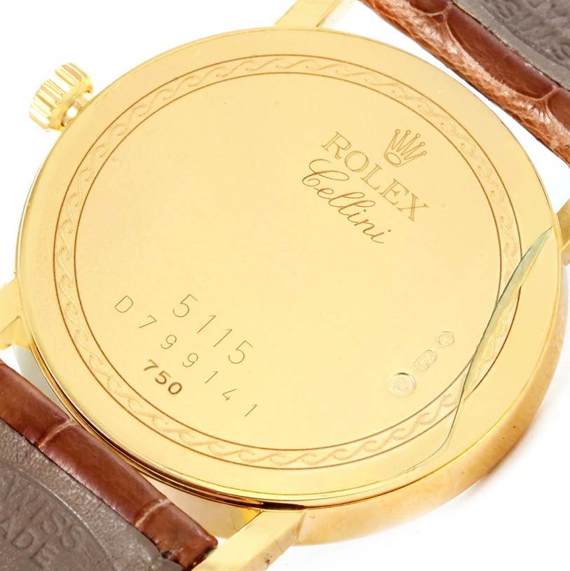 The image shows the back view of a Rolex Cellini 5115 Men
s Yellow Gold Champagne Dial 5115 Men
s Yellow Gold Champagne Dial watch, highlighting the casing, engraving, and part of the leather strap.