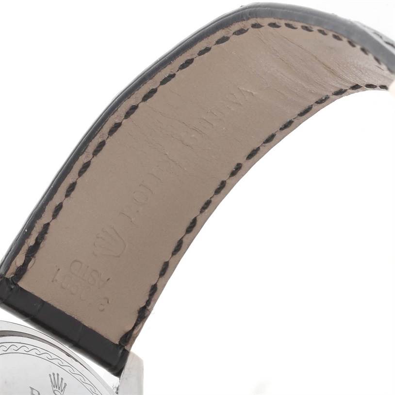 The image shows part of the leather strap and case back of a Rolex Cellini 4243 Men
s White Gold Black Dial 4243 Men
s White Gold Black Dial watch from a close-up angle.