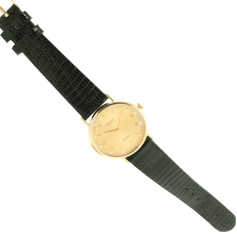 The image shows a top view of a Rolex Cellini 5112 Men's Yellow Gold Champagne Dial 5112 Men's Yellow Gold Champagne Dial watch with a gold round face and a black textured strap.