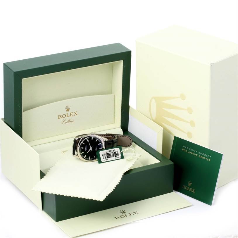 The image shows a Rolex Cellini 4243 Men's White Gold Black Dial 4243 Men's White Gold Black Dial watch at a front angle, displayed with its box, a warranty booklet, and a cleaning cloth.