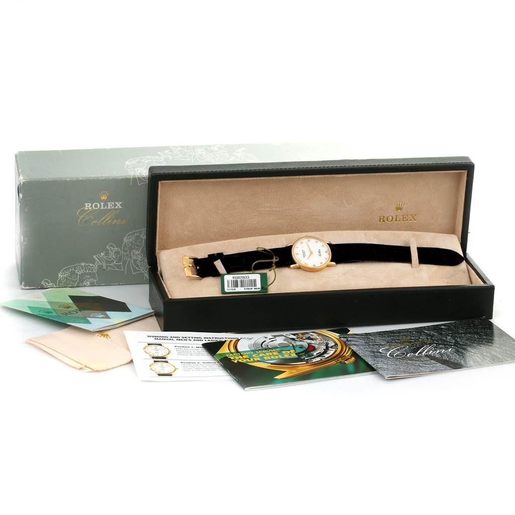 The Rolex Cellini 5115 Men's Yellow Gold Mother of Pearl Dial 5115 Men's Yellow Gold Mother of Pearl Dial watch is shown from a top-down angle in its box, along with various documents and accessories.