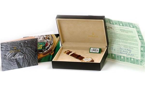 The image shows the Rolex Cellini 5115 Men's Yellow Gold Silver Dial 5115 Men's Yellow Gold Silver Dial watch lying flat in its open box along with accompanying booklets and documents.