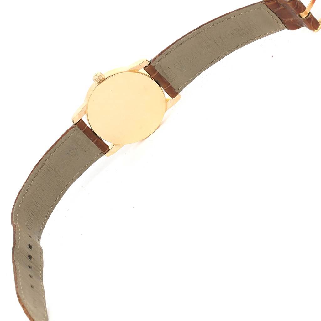 The image shows the backside of a Rolex Cellini 5116 Men's Yellow Gold Grey Dial 5116 Men's Yellow Gold Grey Dial watch with an open leather strap, displaying the case back and part of the crown.