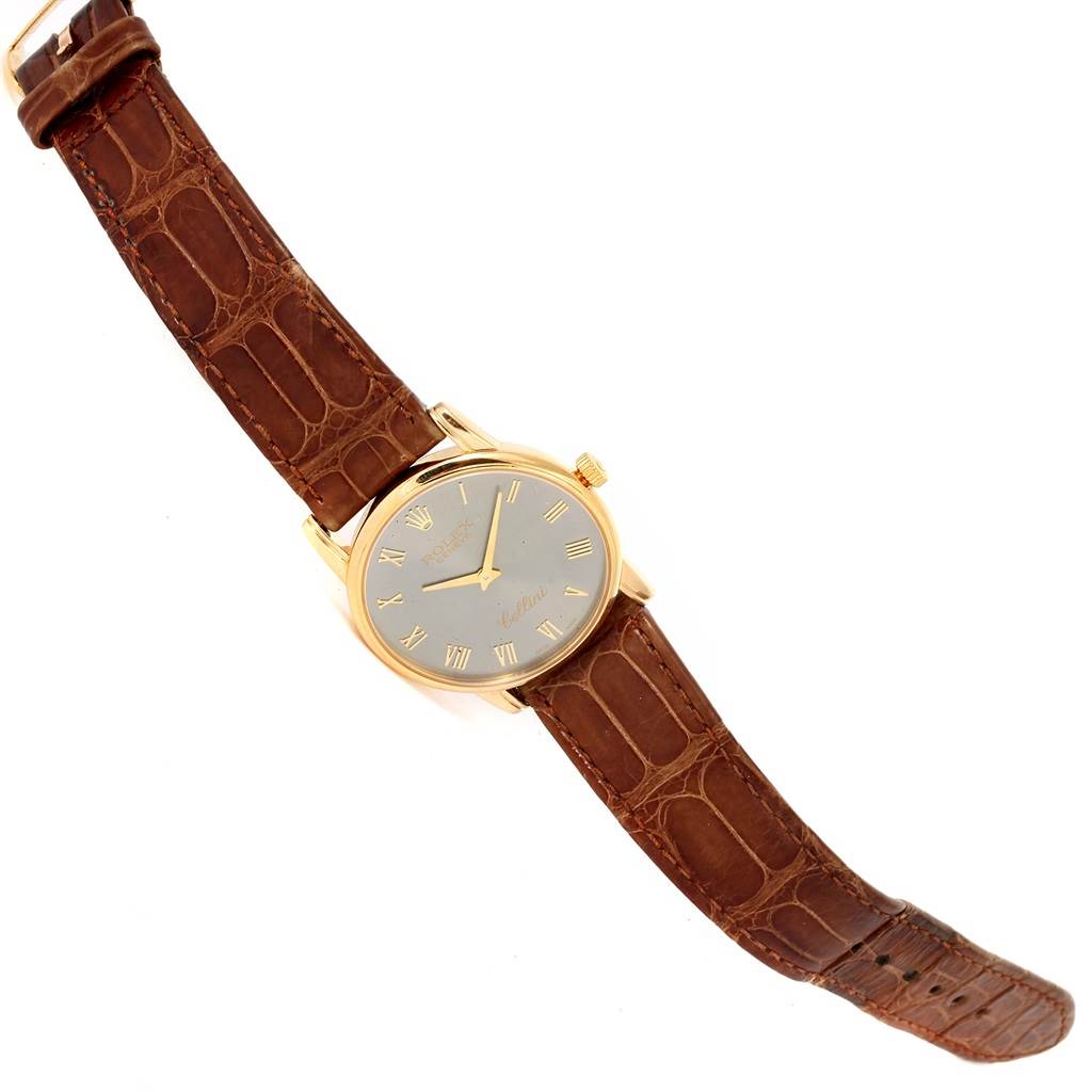 The image shows a Rolex Cellini 5116 Men's Yellow Gold Grey Dial 5116 Men's Yellow Gold Grey Dial watch at an overhead angle, featuring its brown leather strap and gold case with a round dial.