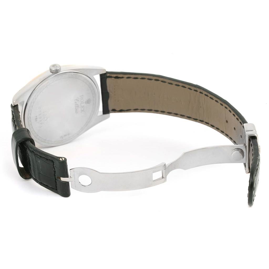 The image shows the back of a Rolex Cellini 4243 Men
s White Gold Black Dial 4243 Men
s White Gold Black Dial watch and its open clasp and leather strap.