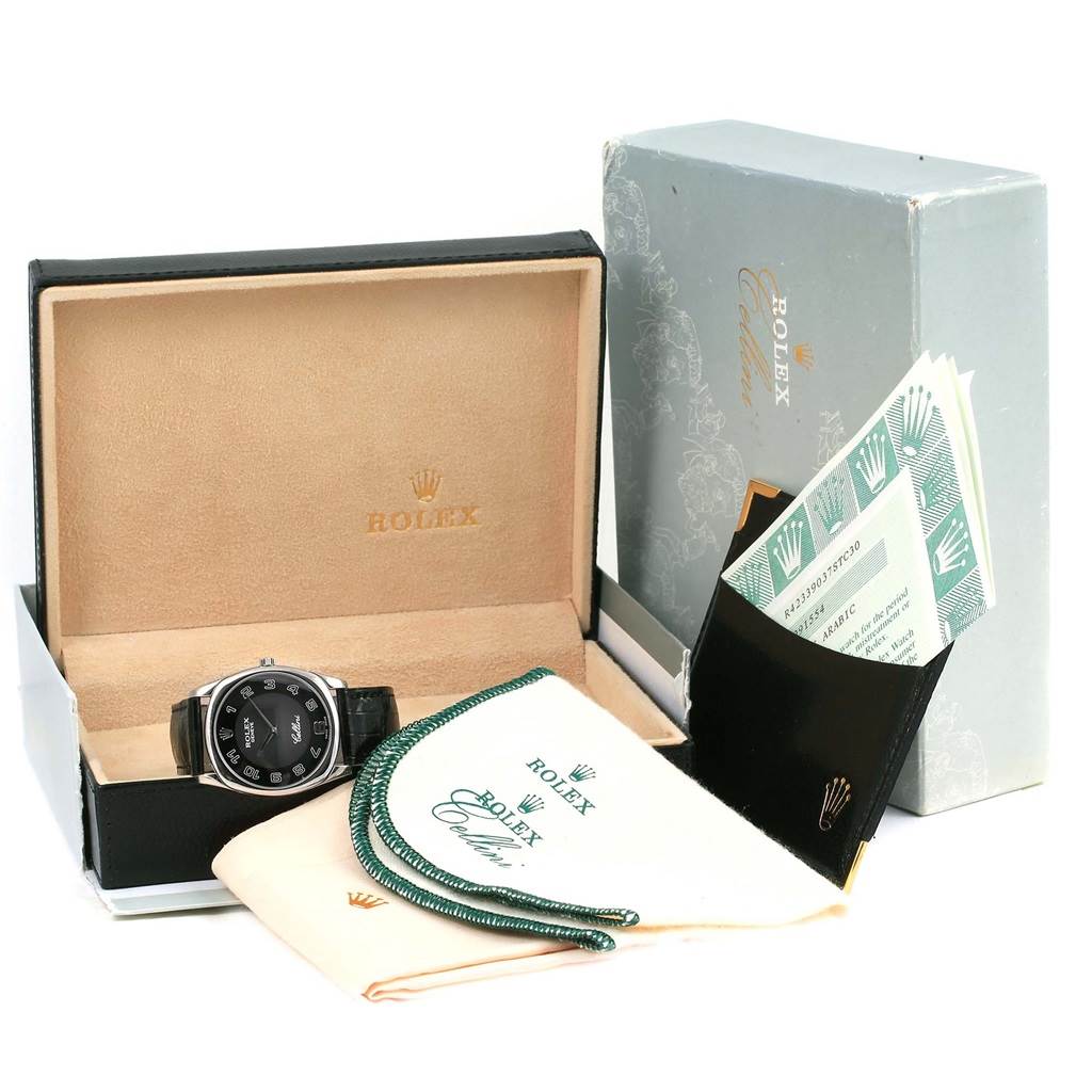 The Rolex Cellini 4233 Men's White Gold Black Dial 4233 Men's White Gold Black Dial watch is displayed in its box with accessories, including manuals, cleaning cloths, and a guarantee card holder.