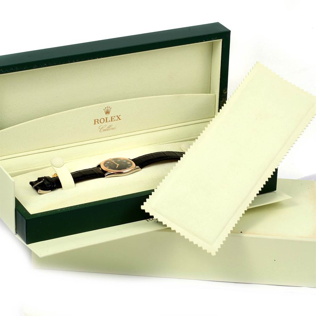 The image shows a Rolex Cellini 4233 White Gold Black Dial 4233 White Gold Black Dial watch at an angle inside its open box, with two cleaning cloths on the side.