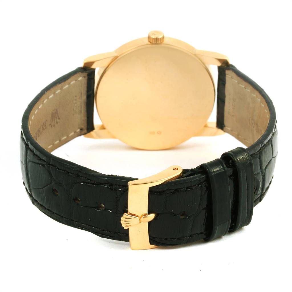 The image shows the back view of a Rolex Cellini 5116 Yellow Gold Grey Dial 5116 Yellow Gold Grey Dial watch with a gold case and black leather strap with a gold buckle.