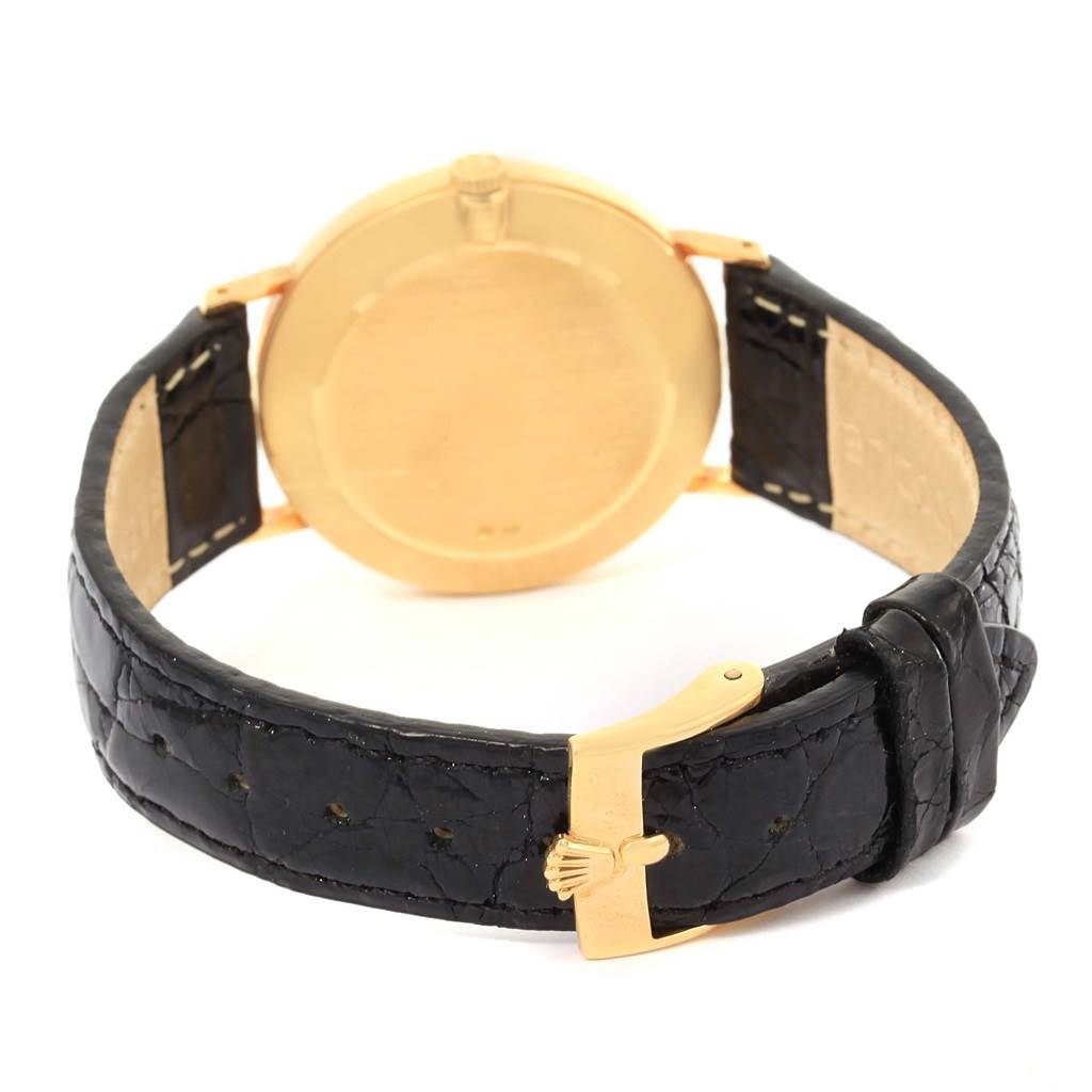 The image shows the back view of a Rolex Cellini 4112 Yellow Gold Champagne Dial 4112 Yellow Gold Champagne Dial watch with a gold case and a black leather strap.