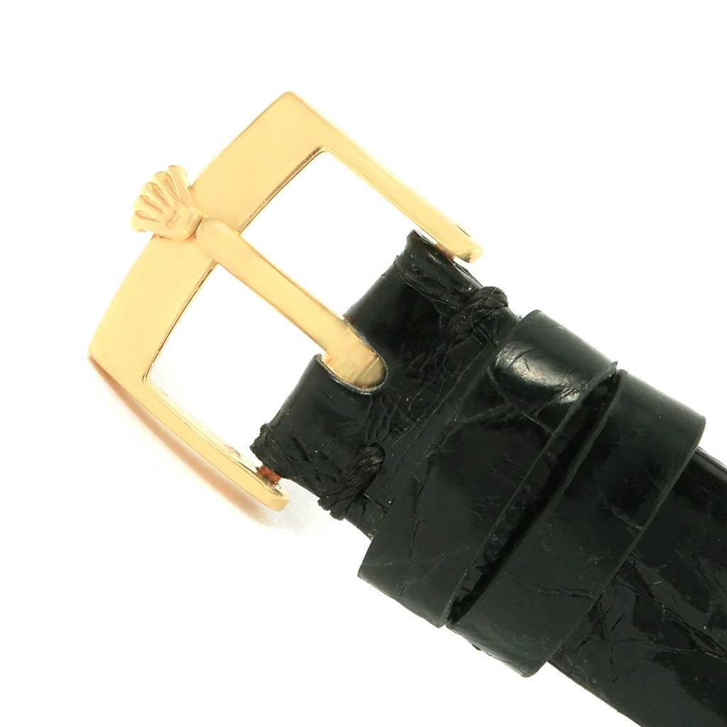 This image shows a close-up of the gold buckle and black leather strap for the Cellini model Rolex watch.