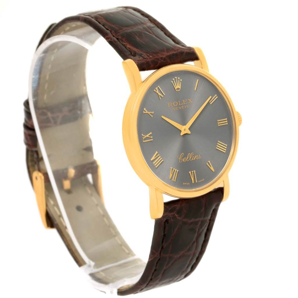 The image shows a Rolex Cellini 5115 Men's Yellow Gold Grey Dial 5115 Men's Yellow Gold Grey Dial watch at an angle, highlighting its gold case, black dial, and leather strap.