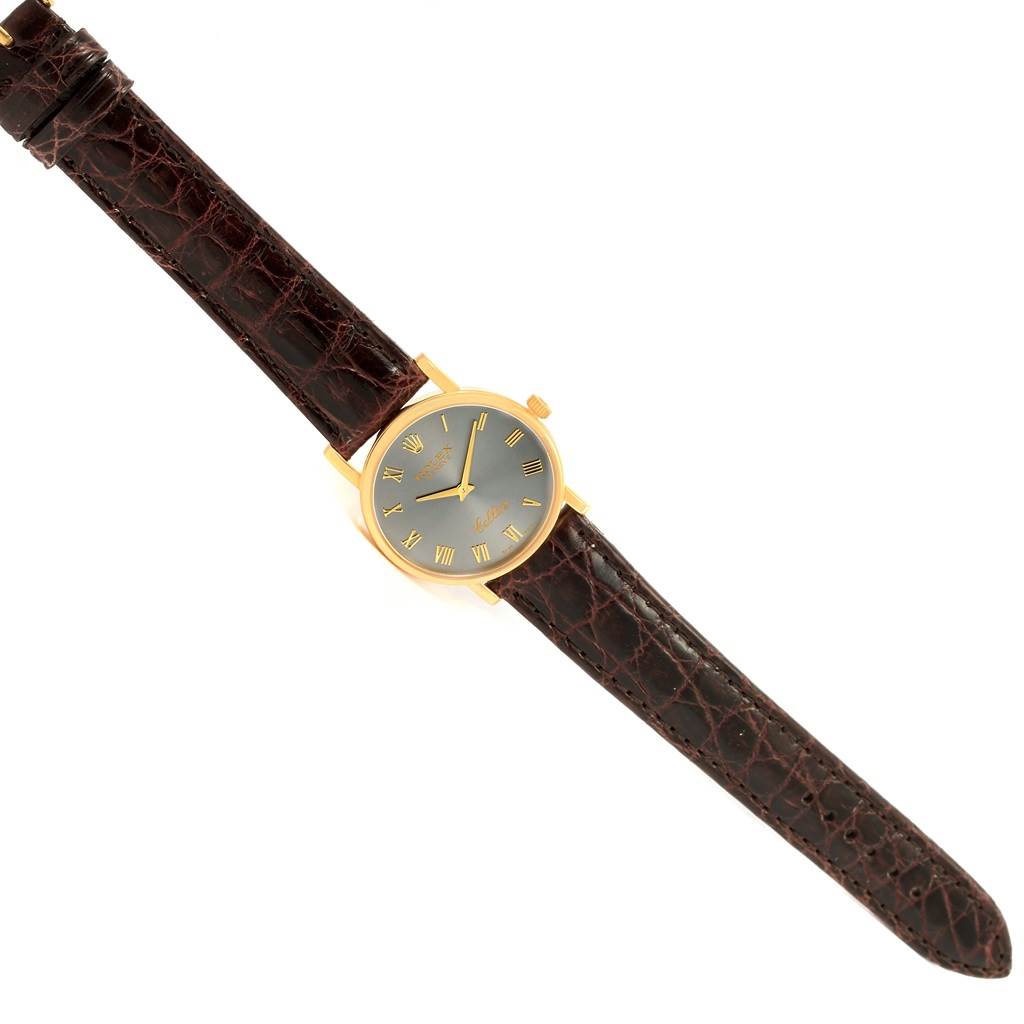 The image shows a Rolex Cellini 5115 Men's Yellow Gold Grey Dial 5115 Men's Yellow Gold Grey Dial watch at an angled perspective, displaying the leather strap, gold case, and face with Roman numerals.