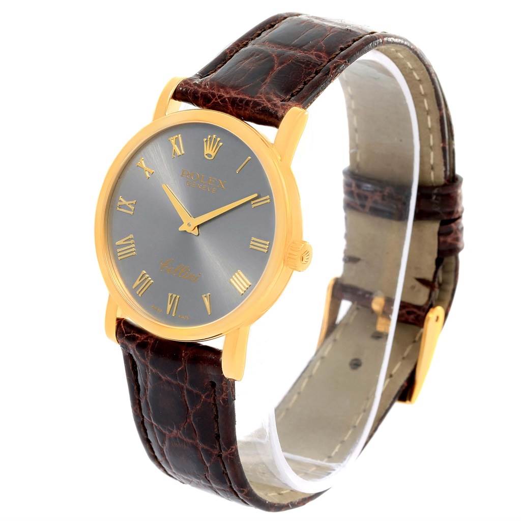 The image shows a Rolex Cellini 5115 Men's Yellow Gold Grey Dial 5115 Men's Yellow Gold Grey Dial watch angled slightly to the right, highlighting its leather strap, gold case, and dial with Roman numerals.
