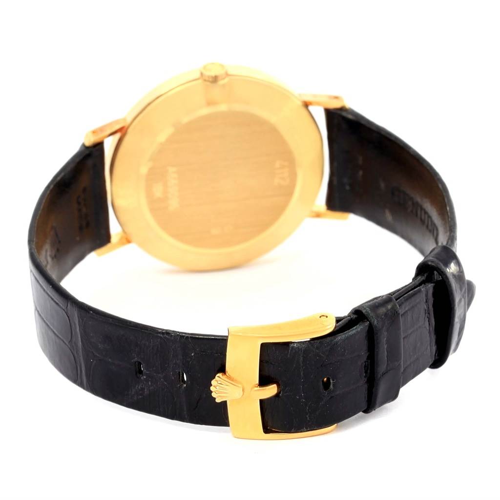 The Rolex Cellini 4112 Men's Yellow Gold Beige Dial 4112 Men's Yellow Gold Beige Dial watch is shown from the back, highlighting its golden case and black leather strap with a golden buckle.