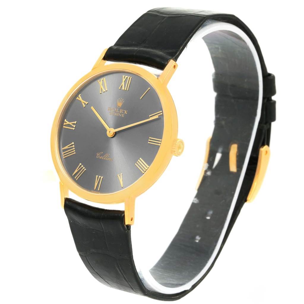 The Rolex Cellini 4112 Men's Yellow Gold Grey Dial 4112 Men's Yellow Gold Grey Dial watch is shown at a three-quarter angle, highlighting its gold case, black strap, and grey dial with Roman numerals.