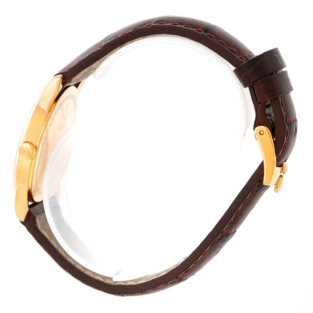 The image shows a side view of a Rolex Cellini 5116 Men's Yellow Gold Beige Dial 5116 Men's Yellow Gold Beige Dial watch, highlighting its gold case, crown, and leather strap with a buckle.