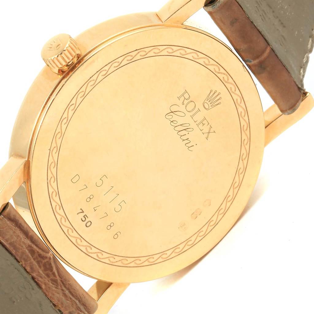 The image shows the back case and crown of a Rolex Cellini 5115 Yellow Gold Mother of Pearl Dial 5115 Yellow Gold Mother of Pearl Dial watch at an angle, along with parts of the leather strap.