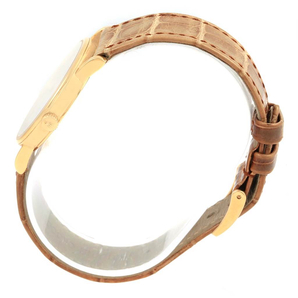 This image shows a side view of a Rolex Cellini 5115 Yellow Gold Mother of Pearl Dial 5115 Yellow Gold Mother of Pearl Dial watch with a gold case and a brown leather strap.