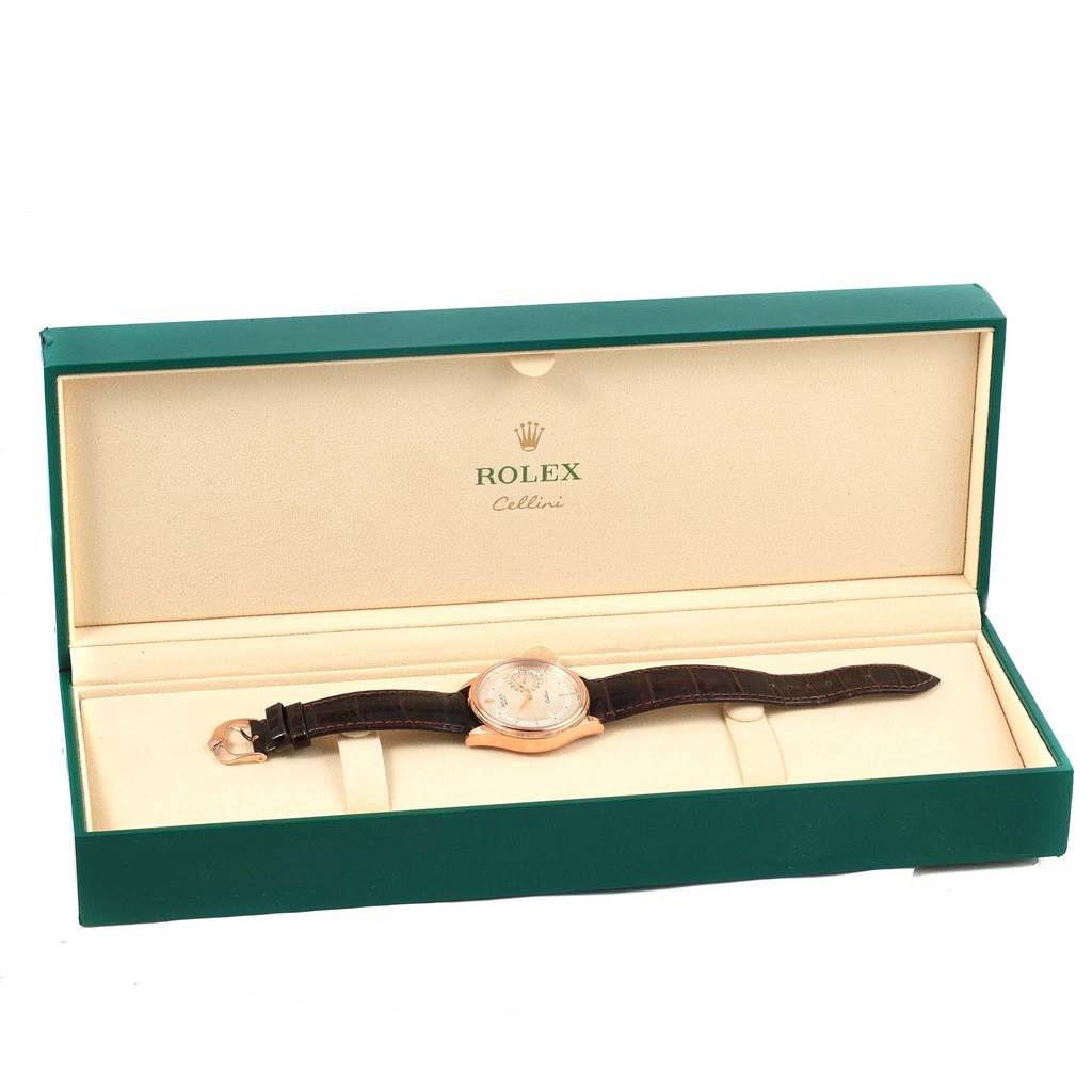 The Rolex Cellini 50515 Men's Rose Gold Silver Dial 50515 Men's Rose Gold Silver Dial watch is displayed in an open green and cream box, showing its face and leather strap from a top-down angle.