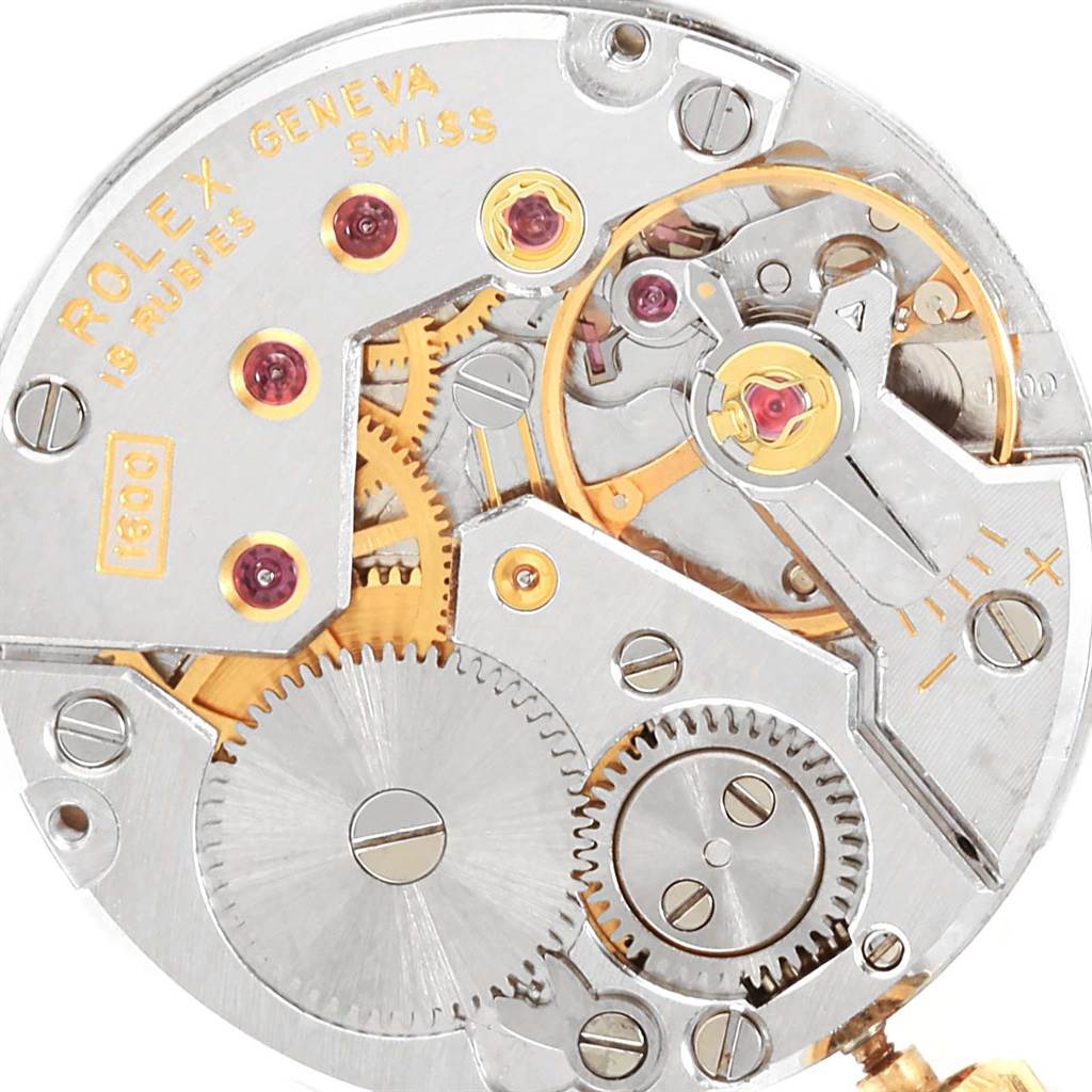 This close-up view shows the intricate internal mechanism of a Rolex Cellini 4015 Men's Yellow Gold White Dial 4015 Men's Yellow Gold White Dial watch, including gears, jewels, and inscriptions.